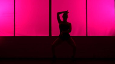 Pembe ışıkla yüksek tepelerde dans eden bir kadının silüeti..