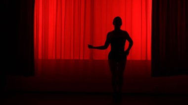 Kırmızı ışıkla yüksek tepelerde dans eden bir kadının silüeti..