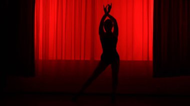 Kırmızı ışıkla yüksek tepelerde dans eden bir kadının silüeti..