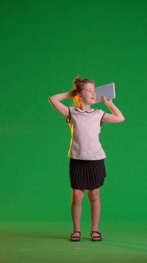 Stüdyoda poz veren liseli kız. Genç liseli kız, krom anahtar yeşil ekran arka planında izole edilmiş mutlu bir jest gösteriyor. Çalışma alanı modeli. Eğitim reklam kavramı.