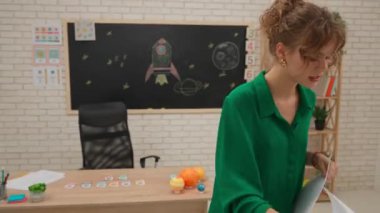 Bir grup ilkokul öğrencisi sınıfta fen bilgisi öğreniyor. Ortaokul öğrencileri ve kızlar astronomi sınıfında oturuyor. Bayan öğretmen çocuklara egzersiz için kağıt çarşaf veriyor. Modern eğitim kavramı.