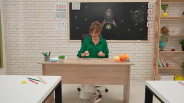 Bir grup ilkokul öğrencisi sınıfta fen bilgisi öğreniyor. Astronomi sınıfındaki orta okul öğrencileri ve kızlar. Kadın öğretmen güneş sistemiyle konuşuyor, dünya kartını gösteriyor. Modern eğitim kavramı.