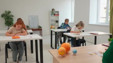 Bir grup ilkokul öğrencisi sınıfta fen bilgisi öğreniyor. Ortaokul öğrencileri ve kızlar astronomi sınıfında oturuyor. Öğrenci ödevini bitirdi ve öğretmenine kâğıt çarşaf verdi. Modern eğitim kavramı