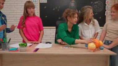 Bir grup ilkokul öğrencisi sınıfta fen bilgisi öğreniyor. Ortaokul öğrencileri ve kızlar astronomi sınıfında oturuyor. Bayan öğretmen, çocukların yanında durduğu gezegen modellerini açıklıyor. Modern eğitim kavramı.