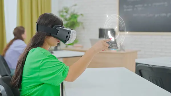 stock image Student in green shirt uses a virtual reality headset to interact with a sophisticated virtual interface, highlighting the integration of cutting-edge VR technology in educational environments.