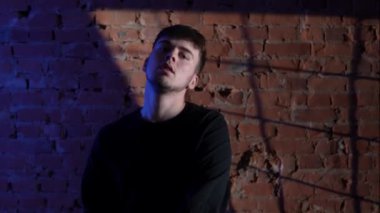 Siyah elbiseli genç adam kırmızı tuğla duvara karşı hip hop dansı yapıyor..
