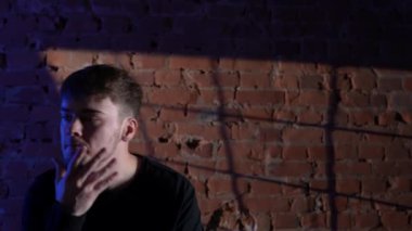 Siyah elbiseli genç adam kırmızı tuğla duvara karşı hip hop dansı yapıyor..
