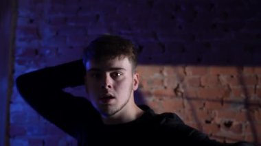 Siyah elbiseli genç adam kırmızı tuğla duvara karşı hip hop dansı yapıyor..