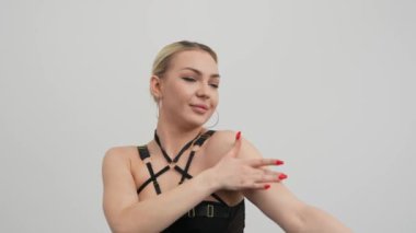 Siyah elbiseli genç bir kadın siyah zemini olan beyaz bir odada yüksek tepelerde dans ediyor..