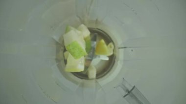 Olgun sulu meyvelerin karışımının üst görüntüsü bir mikserin cam şişesine düşüyor. Sağlıklı bir diyet smoothie yapmak için armut, muz, greyfurt ve limon dilimleri. Sağlıklı yiyecekler. Kapat..