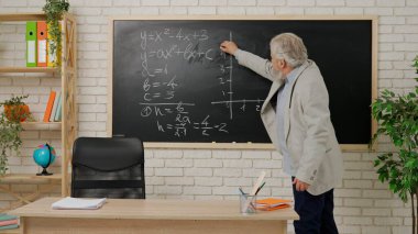 Ders sırasında oditoryumda öğretmen. Sınıfta tahtaya oturup cebir formülü numunesi yazan yaşlı bir adam üniversite profesörü. Eğitim kavramı.