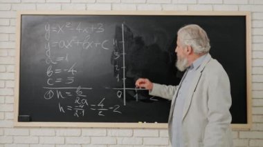 Ders sırasında oditoryumda öğretmen. Karatahta tahtasının önünde duran yaşlı adam üniversite profesörü dersi açıklıyor, cebir örneği yazıyor, kapat. Eğitim kavramı.