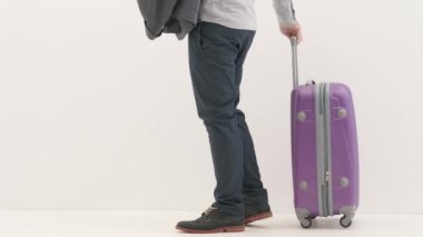 Havaalanı koridorunda bagajlı bir gezgin. Uluslararası havaalanında bavuluyla seyahat eden turist beyaz arka planda izole edilmiş uçuş ve ceket bekliyor. Seyahat kavramı.