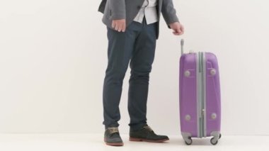 Havaalanı koridorunda bagajlı bir gezgin. Seyahat eden iş adamı turist, uluslararası havaalanında bavulun sapını tutuyor, beyaz arka planda izole bir şekilde uçuşu bekliyor. Seyahat kavramı.