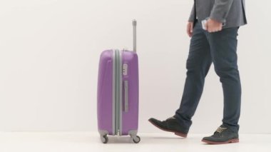 Havaalanı koridorunda bagajlı bir gezgin. Seyahat eden iş adamı turist uçuş biletlerini ve pasaportunu kontrol ediyor, bavulunu beyaz arka planda uluslararası havaalanında tek başına tutuyor. Seyahat kavramı.