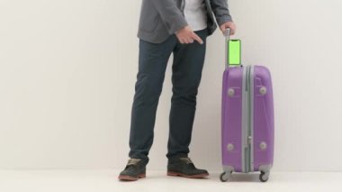 Havaalanı koridorunda bagajlı bir gezgin. Uluslararası havaalanı noktalarında bavuluyla seyahat eden iş adamı turist akıllı telefon anahtar yeşil ekranda, beyaz arka planda izole edilmiş..