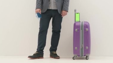Havaalanı koridorunda bagajlı bir gezgin. Beyaz arka planda izole edilmiş uluslararası havaalanında bavul ve akıllı telefon kroma anahtar yeşil ekranlı seyahat eden iş adamı turisti. Seyahat kavramı.
