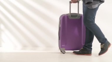 Havaalanı koridorunda bagajlı bir gezgin. Uluslararası havaalanında bavuluyla seyahat eden turist beyaz arka planda izole bir şekilde uçuşu bekliyor. Seyahat kavramı.