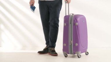 Havaalanı koridorunda bagajlı bir gezgin. Uluslararası havaalanında bavuluyla seyahat eden turist beyaz arka planda izole bir şekilde uçuşu bekliyor. Seyahat kavramı.