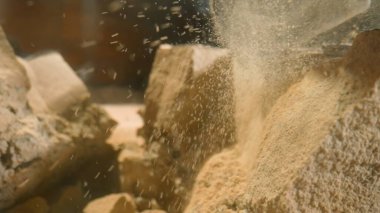 Matkap sert, parçalanmış taş malzemeyi delip inşaat ekipmanlarının ham gücünü yakalıyor. Kaya dokusu ve matkap delip geçerken dağılan ince parçacıklar.