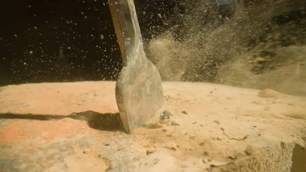 stock image Drill penetrating stony ground. Dynamic action of a hammer drill impacting a sandy surface, highlighting the dispersion of sand particles. Industrial power in action.