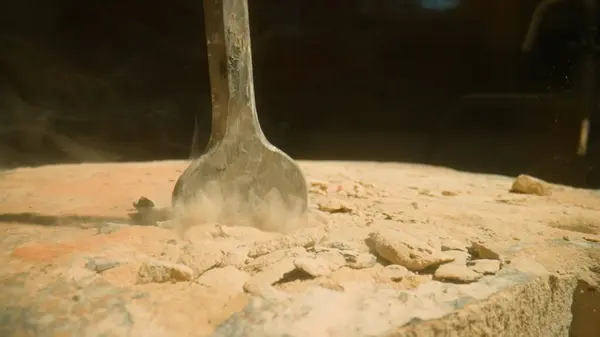 stock image Drill penetrating stony ground. Dynamic action of a hammer drill impacting a sandy surface, highlighting the dispersion of sand particles. Industrial power in action.