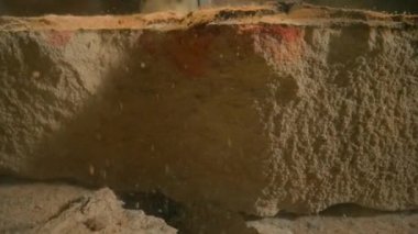 Matkap sert, parçalanmış taş malzemeyi delip inşaat ekipmanlarının ham gücünü yakalıyor. Kaya dokusu ve matkap delip geçerken dağılan ince parçacıklar.