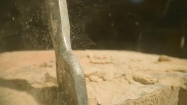 Matkap sert, parçalanmış taş malzemeyi delip inşaat ekipmanlarının ham gücünü yakalıyor. Kaya dokusu ve matkap delip geçerken dağılan ince parçacıklar.