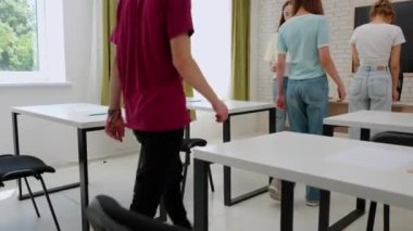 Oditoryumdaki bir grup genç kız ve erkek öğrenci. Sınav sorularıyla kağıttan çarşaf alan liseli gençler, öğretmenler masasından sınava hazırlanıyorlar. Modern eğitim kavramı.