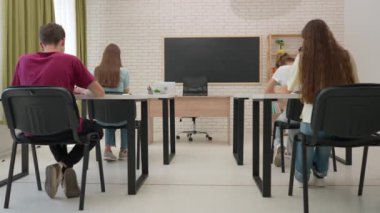 Oditoryumdaki bir grup genç kız ve erkek öğrenci. Sınıftaki liseli gençler, sıralarında oturup sınav yazıyorlar, kağıt çarşaflarla test görevleri yapıyorlar. Modern eğitim kavramı.