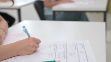 Oditoryumdaki bir grup genç kız ve erkek öğrenci. Lise öğrencileri sıralarında oturup sınav yazıyorlar, sınav ödevlerini kağıt üzerinde yapıyorlar, cevapları kontrol ediyorlar, kapatıyorlar. Modern eğitim kavramı.