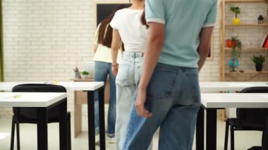 Oditoryumdaki bir grup genç kız ve erkek öğrenci. Sınıftaki liseli gençler, öğretmenler masasına yürüyüp sınav kağıtlarını alıyorlar. Modern eğitim kavramı.