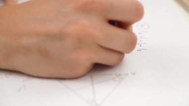 Oditoryumdaki bir grup genç kız ve erkek öğrenci. Sınıftaki liseli gençler, yakın çekim yapan kız matematik sınavı yazıyor, kağıt üzerinde iş çözüyorlar. Modern eğitim kavramı.
