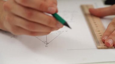 Oditoryumdaki bir grup genç kız ve erkek öğrenci. Sınıftaki liseli gençler, matematik sınavı yazan, cetvel ve kalemle çizen, ödevlerini yapan yakın çekim kızı. Modern eğitim kavramı.