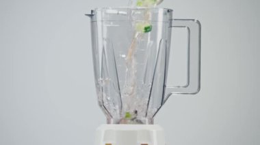 Taze marul yaprakları, salatalık, domates, kereviz dilimleri ve su şeffaf bir blender şişesine dökülüyor. Taze, sağlıklı bir sebze püresi yapıyorum..