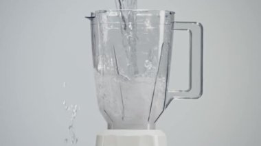 Su miksere dökülüyor, sıçramalar yaratıyor. Karıştırıcıda temiz su karışımı var.