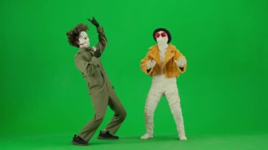 Cadılar Bayramı ve tuhaf reklam yaratıcı konsepti. Krom anahtar yeşil ekran arka planında mumya bandajlı birinin portresi. Karaokede şarkı söyleyen manyak mikrofonlu mumya onunla dans ediyor..