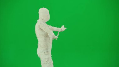 Cadılar Bayramı ve tuhaf reklam yaratıcı konsepti. Krom anahtar yeşil ekran arka planında mumya bandajlı birinin portresi. Annecik beyaz kurdelelerle kaplanmış yürüyordu ve dans ediyordu.