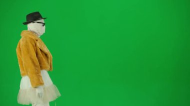 Cadılar Bayramı ve tuhaf reklam yaratıcı konsepti. Krom anahtar yeşil ekran arka planında mumya bandajlı birinin portresi. Kürk giymiş ve gözlük takmış annem podyumda yürüyor..