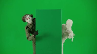 Cadılar Bayramı ve tuhaf reklam yaratıcı konsepti. Krom anahtar yeşil ekran arka planında mumya bandajlı birinin portresi. Annem ve manyak boş tahtada başparmaklarını kaldırarak duruyorlar..
