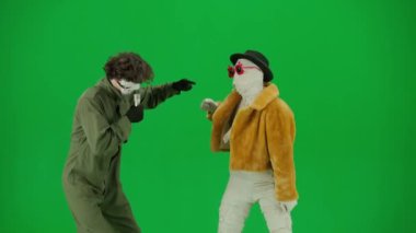 Cadılar Bayramı ve tuhaf reklam yaratıcı konsepti. Krom anahtar yeşil ekran arka planında mumya bandajlı birinin portresi. Karaokede şarkı söyleyen manyak mikrofonlu mumya onunla dans ediyor..