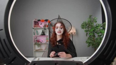 Kadın nüfuzlu kişi canlı video makyaj dersi veriyor. Cadı kostümlü genç kadın güzellik blogcusu akıllı telefondaki cadılar bayramı partisi makyajı için video eğitmeni, izleyicilerle konuşuyor, kozmetik gösteriyor..