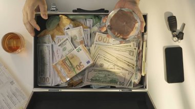Adamın en iyi görüntüsü, içinde avro dolar nakit para, banknotlar ve para çantaları olan bavulu açar. Rüşvet alır ya da kredi olarak borç para alır. Nakit ödeme ile hizmet veya ürün için ödeme yapan erkek
