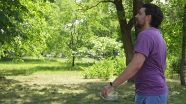 Dışarıda parkta badminton oynamaktan zevk alan iki arkadaş. Bir kadın ve bir erkek aktif olarak badminton oynuyor ve raketlerle bir mekik horozuna vuruyorlar. Yavaş çekim.