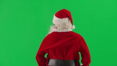 Noel ve Yeni Yıl yaratıcı konsepti. Krom anahtar yeşil ekranda Noel Baba kılığında bir adam portresi. Kırmızı kıyafetli Noel Baba etrafta dolanıp insanları selamlıyor. Arka plan