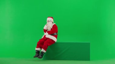Noel ve Yeni Yıl yaratıcı konsepti. Krom anahtar yeşil ekranda Noel Baba kılığında bir adam portresi. Noel Baba kıyafetli, düşünceli, pozitif ruh haliyle geliyor..
