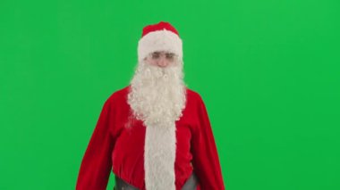 Noel ve Yeni Yıl yaratıcı konsepti. Krom anahtar yeşil ekranda Noel Baba kılığında bir adam portresi. Kırmızı kıyafetli, sakallı ve bıyıklı Noel Baba etrafa bakıyor..