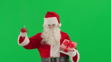 Noel ve Yeni Yıl yaratıcı reklam konsepti. Kromatonlu yeşil ekrana karşı Noel Baba kostümü giymiş bir adamın portresi. Kırmızı kıyafetli Noel Baba içinde hediyeler taşıyan ve zil çalan bir kutu taşıyor.