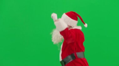 Noel ve Yeni Yıl yaratıcı konsepti. Krom anahtar yeşil ekranda Noel Baba kılığında bir adam portresi. Kırmızı elbiseli Noel Baba komik dans ediyor..