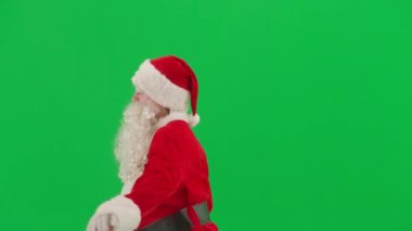 Noel ve Yeni Yıl yaratıcı konsepti. Krom anahtar yeşil ekranda Noel Baba kılığında bir adam portresi. Kırmızı elbiseli Noel Baba komik dans ediyor..